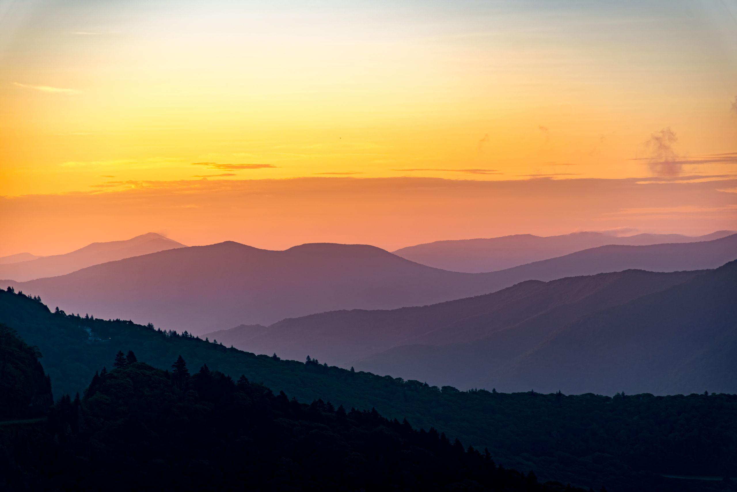 Beautiful sunset over misty mountain silhouettes in a serene landscape.